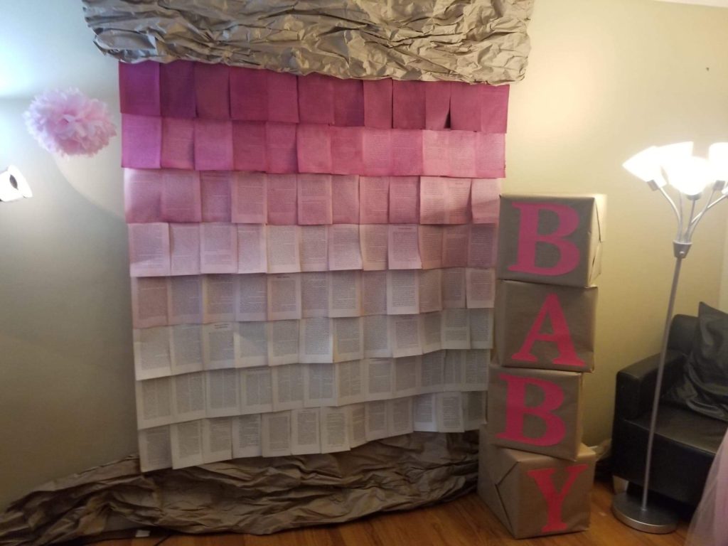 a picture of boxes spelling out 'baby' and pink pages on a wall as a photo backdrop for a baby shower