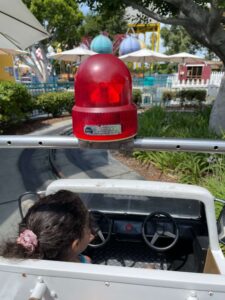 a toddler riding in the front of a miniature rescue vehicle at adventure city