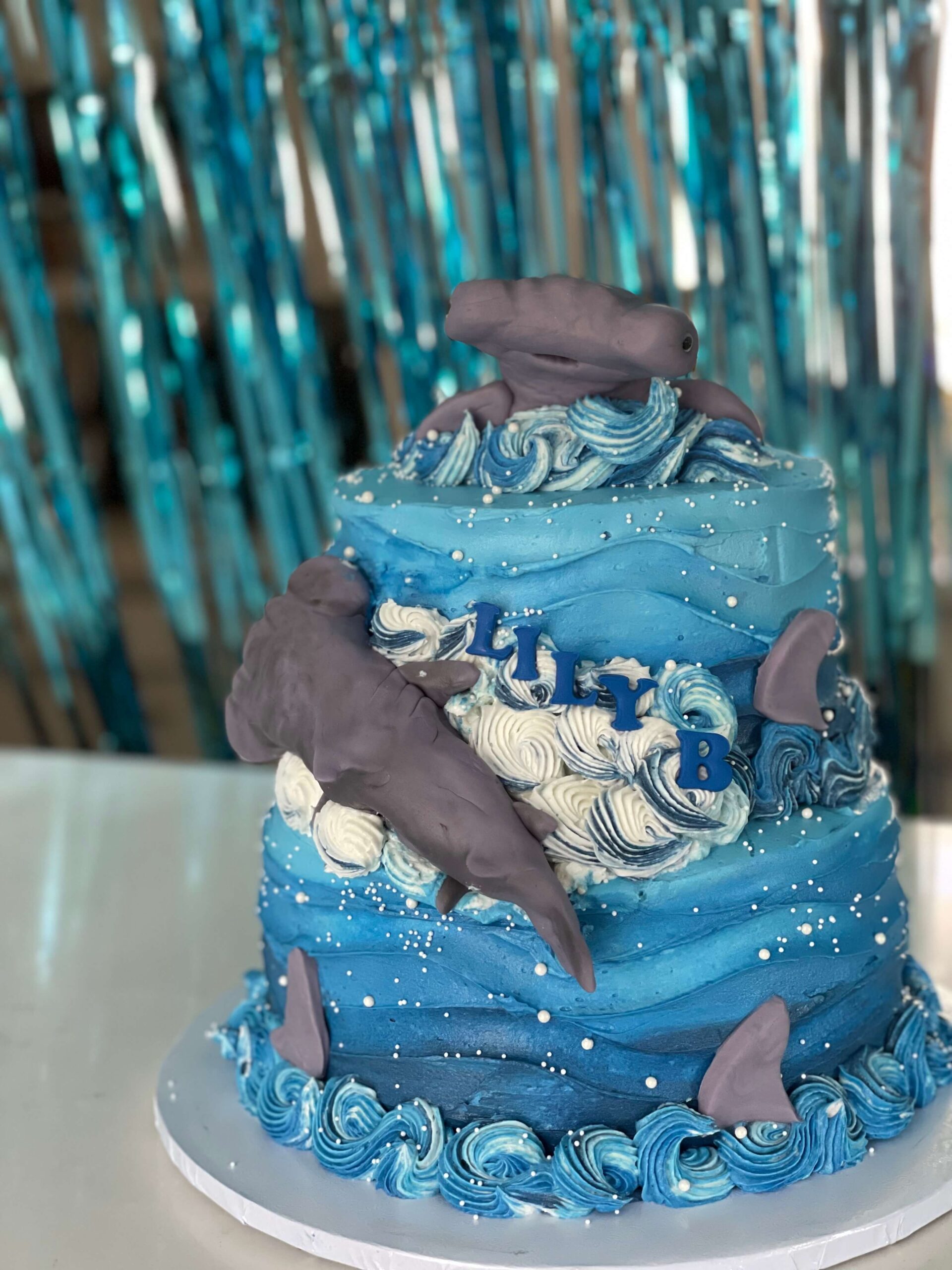 a blue two-tier cake with hammerheads on it