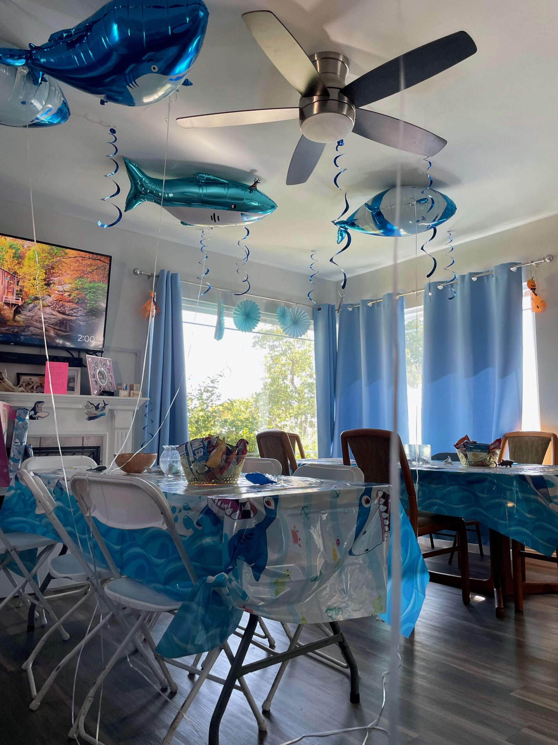 inside of a house with shark balloons and a shark tablecloth
