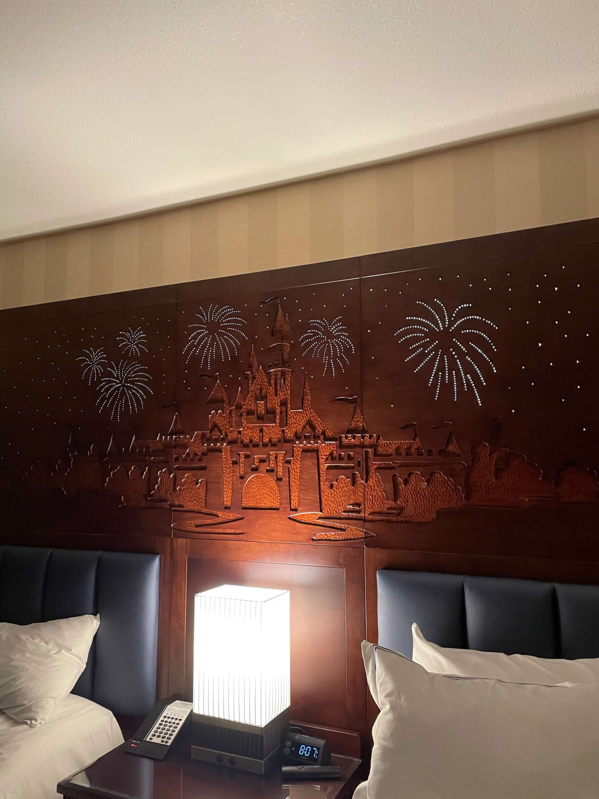 a wooden headboard with light-up fireworks etched into it from the disneyland hotel